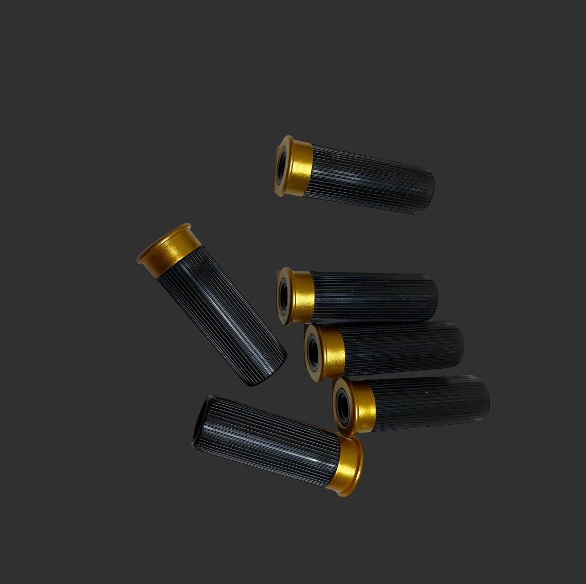 Several black and gold cylindrical objects are scattered against a dark background, resembling the sleek design of a BlasterMasters M1887 Foam Shell Shotgun.