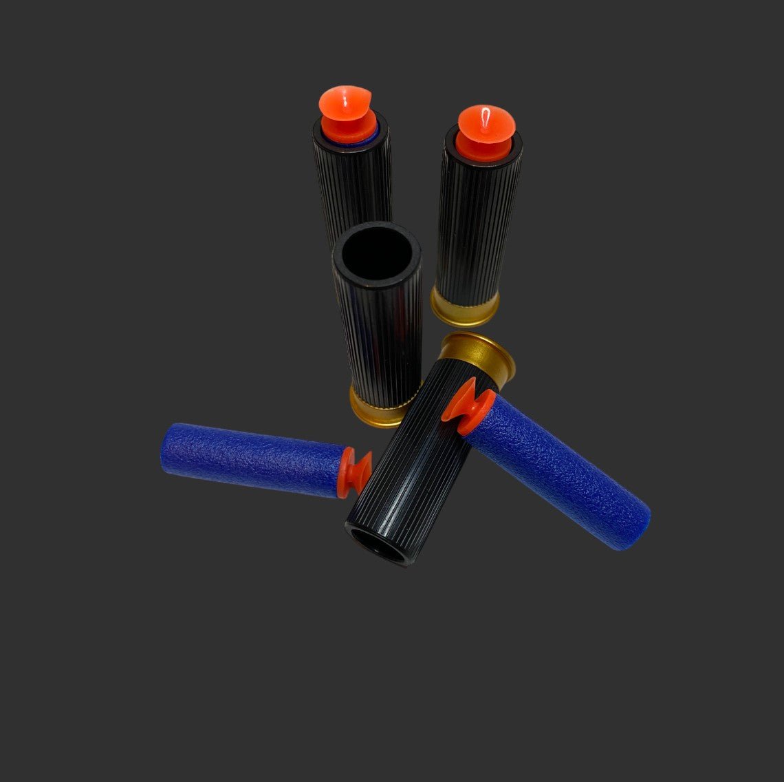 Four black cylindrical containers with ribbed exteriors and orange caps, arranged in a circular pattern on a dark background. Two containers feature blue sleeves similar to those found in the M1887 Foam Shell | Shotgun sets by BlasterMasters.