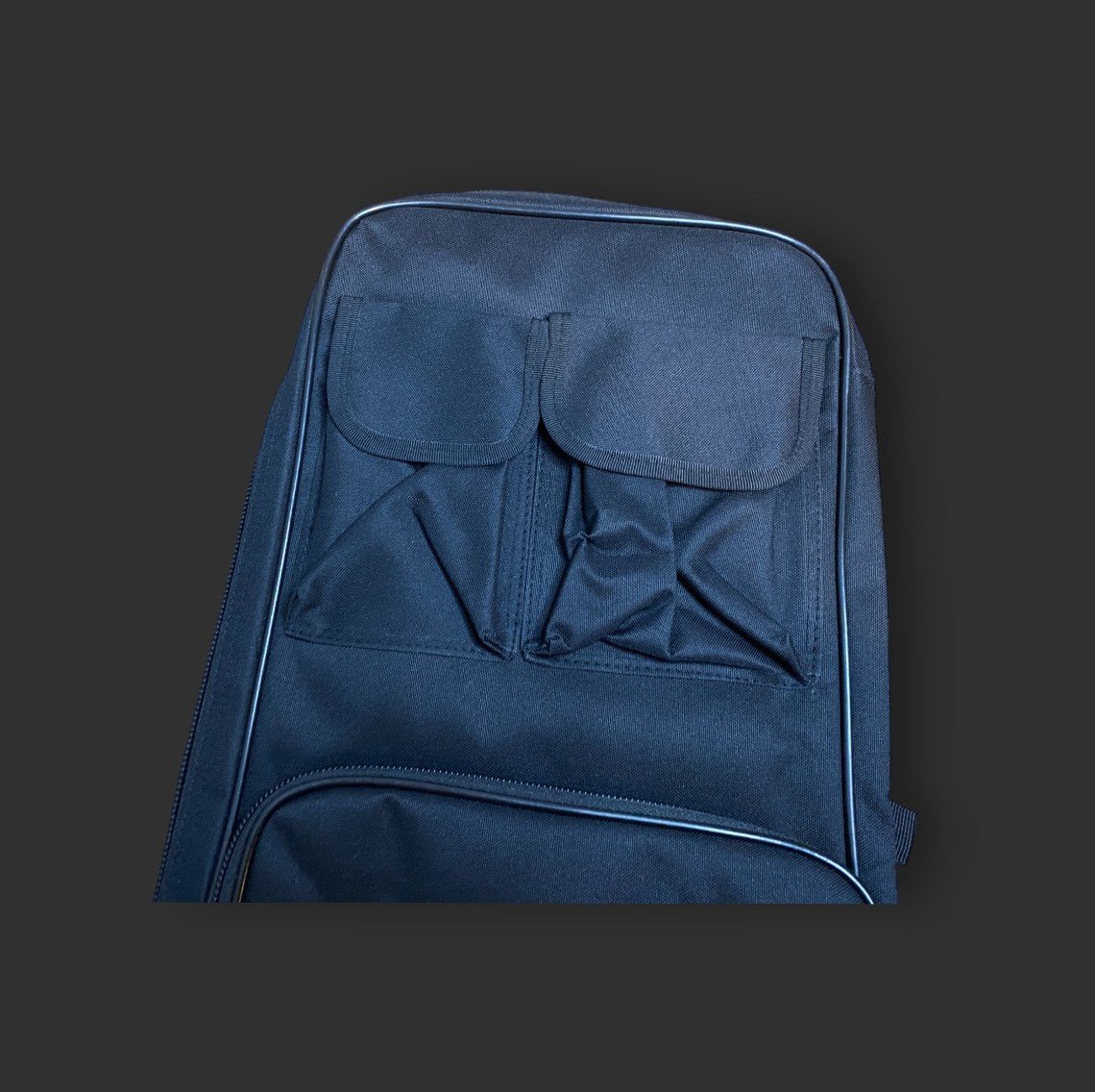 A navy blue 36'' dual gun backpack made from water-resistant 600D nylon, featuring two front pockets and a zipper by BM, photographed against a dark gray background.