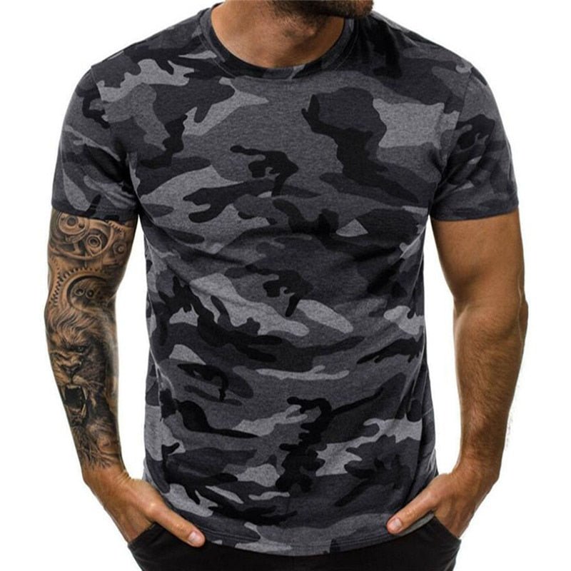 A man with a tattooed arm sporting a BlasterMaster Camo T-Shirt stands casually with his hands in his pockets.