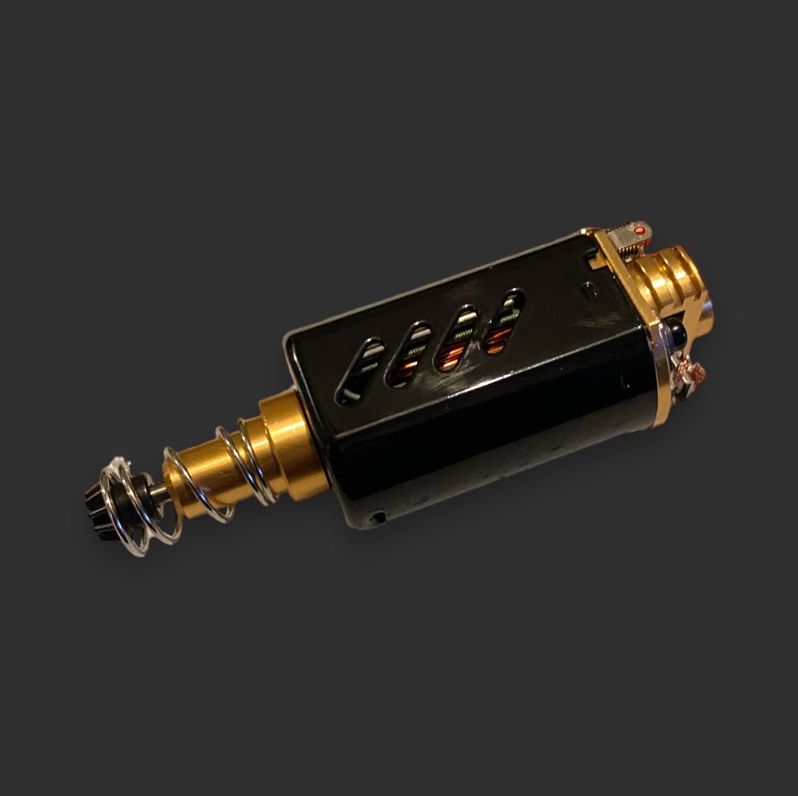 A close-up image of a BlasterMasters CHIHAI MOTOR 11.1V-39000RPM M150 with a black casing and gold-colored components, featuring a visible coiled wire spring, metallic connector at one end, and a neodymium magnet enhancing its efficiency.