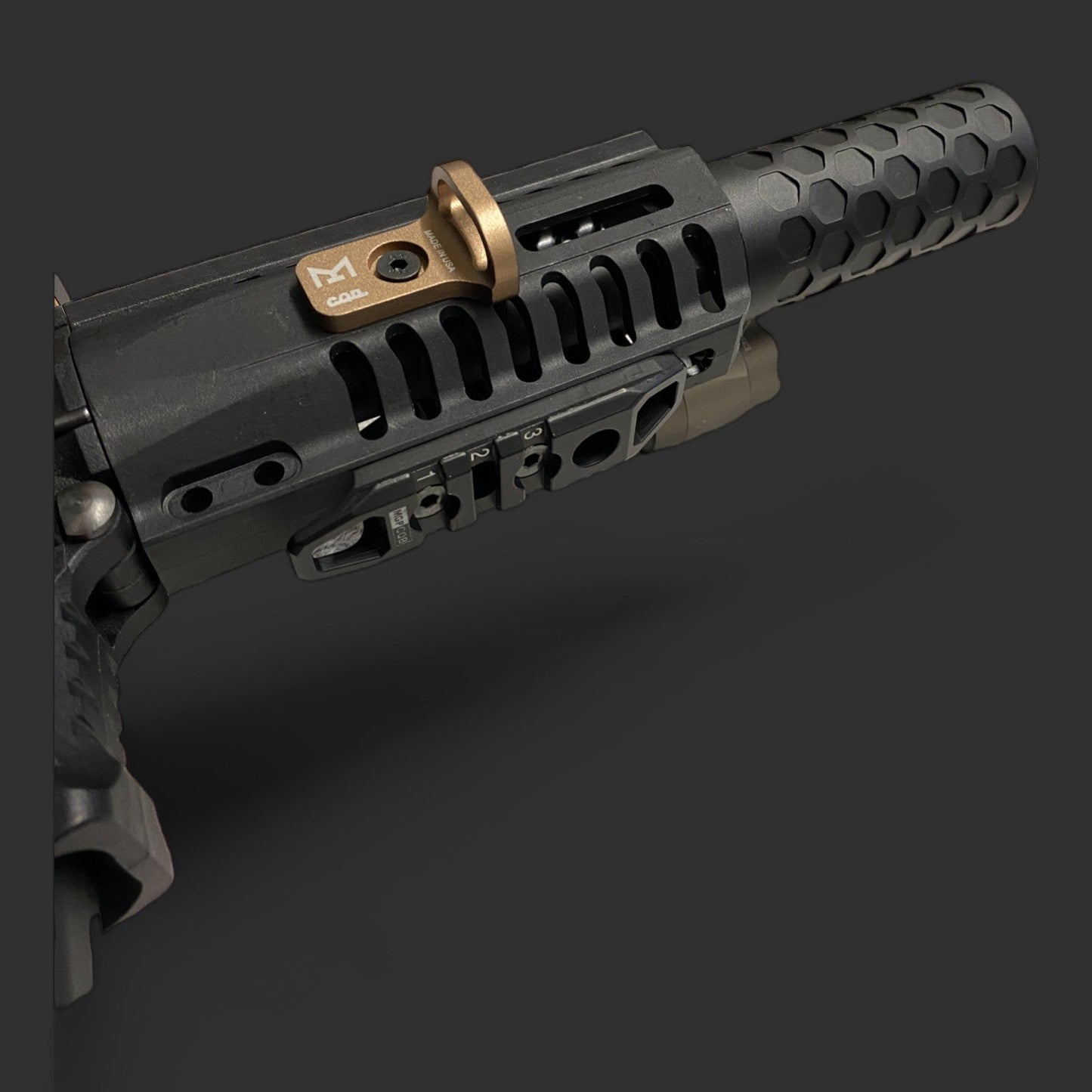 A close-up image of a black firearm barrel highlights its honeycomb-patterned handguard and attached CQD MLOK Forward Sling Mount by MLOCK, showcasing tactical performance with MLOK compatibility.