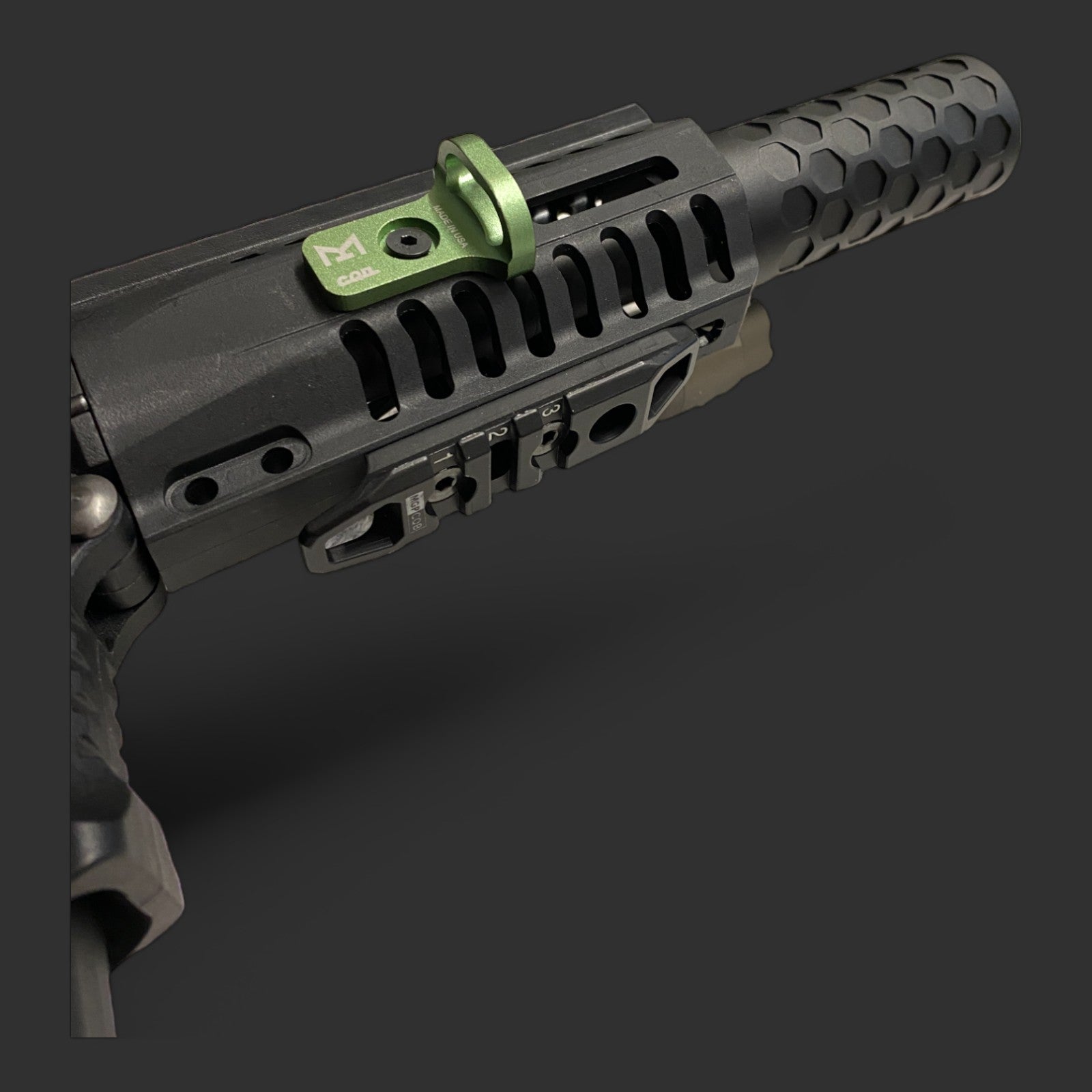 Close-up of a black firearm barrel with a green CQD MLOK Forward Sling Mount from MLOCK ensuring tactical performance on a dark background.