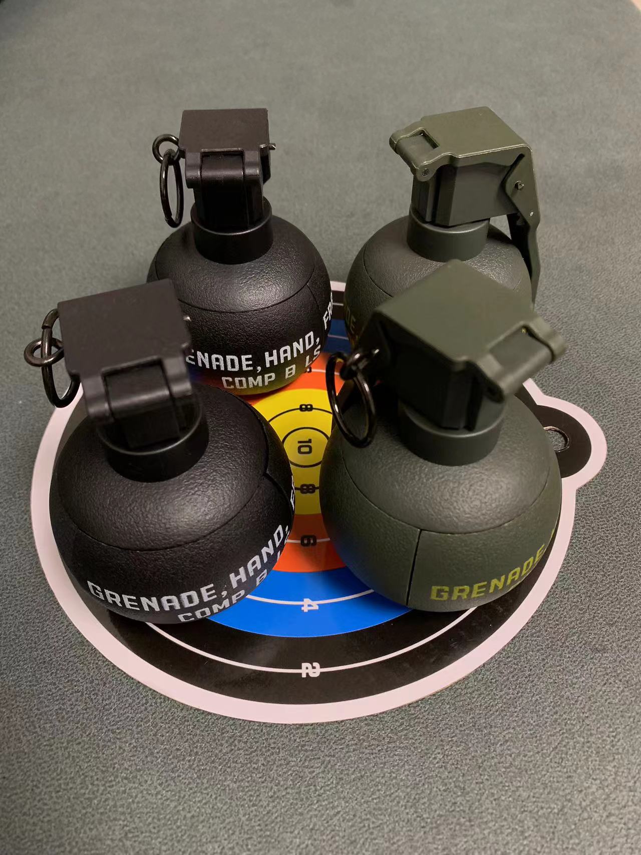 Four BlasterMaster G4 toy hand grenades, two black and two green, are displayed on a multi-colored target mat with concentric circles, ready to unleash chaos in your next backyard battle.