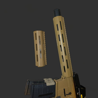 A partially disassembled tan and black rifle, featuring the Honey badger Handguard from BlasterMasters Upgrades, is displayed against a dark background. The handguard is detached and positioned above the remaining portion of the firearm.