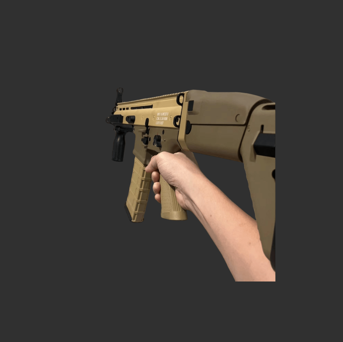 A tan-colored tactical rifle, the DK SCAR Pro Gelblaster by DK, featuring a sophisticated Mosfet System, is being held by a person's right hand against a plain dark background.